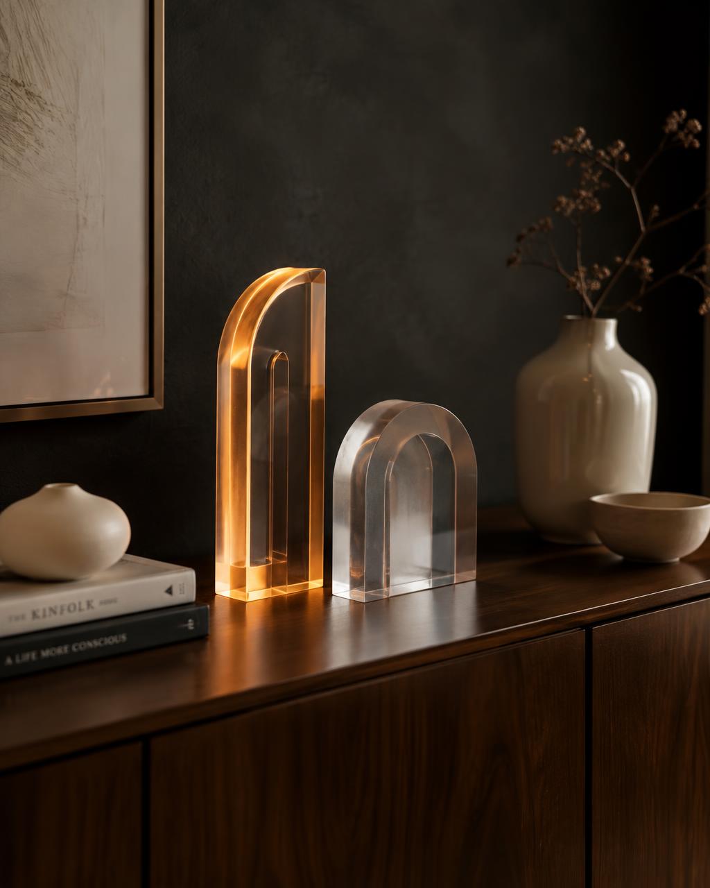 Translucent acrylic décor pieces edged with warm amber light on a walnut console