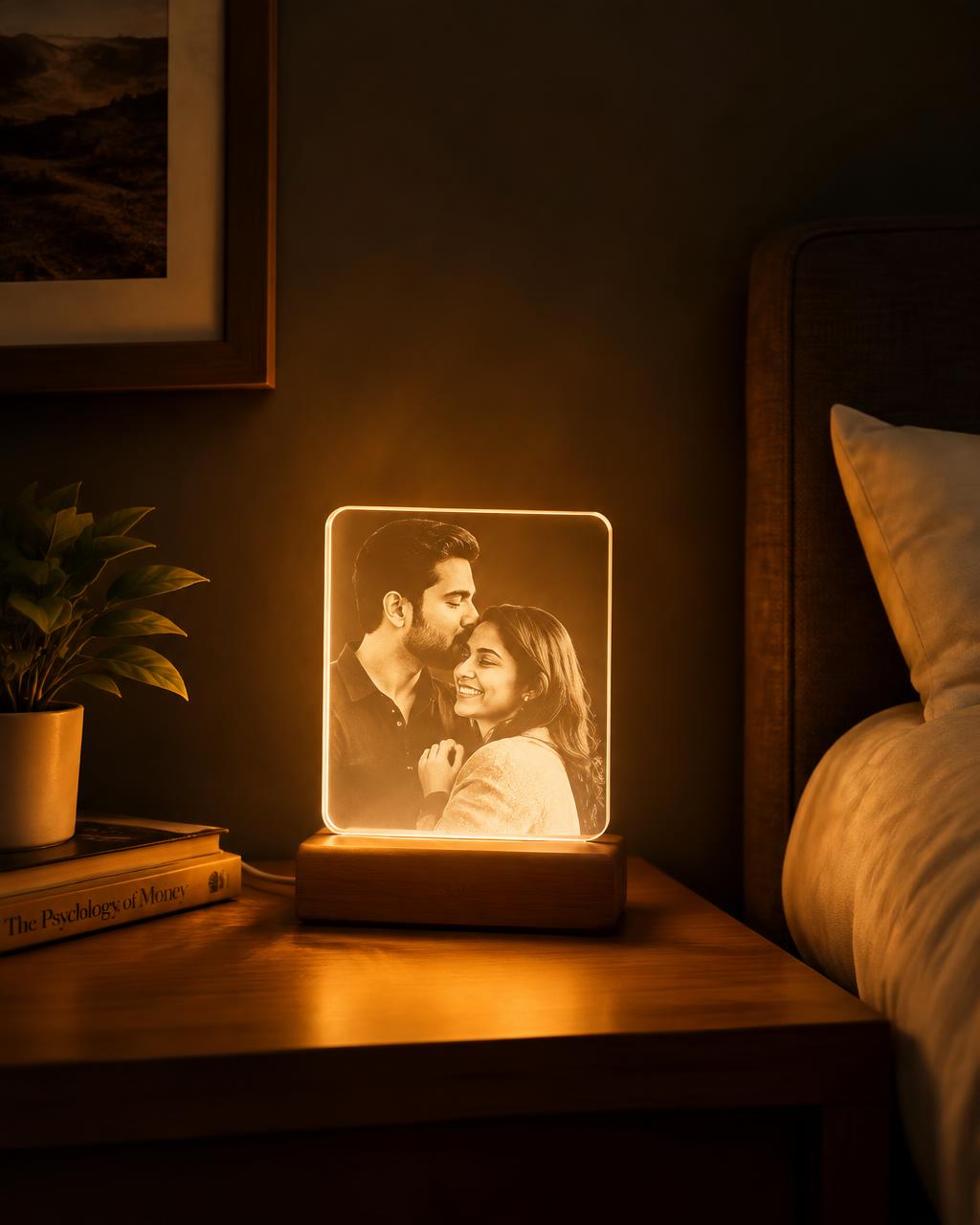 An acrylic lamp with an engraved couple portrait glowing on a bedside table